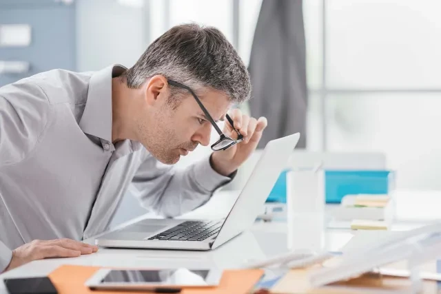 man squinting at computer screen