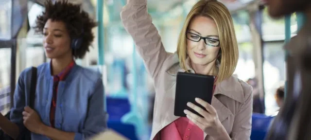 Woman in glasses reading tablet on bus