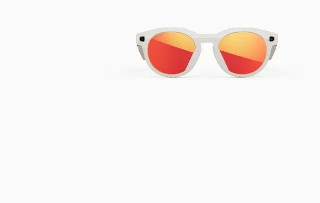 A pair of modern white sunglasses with round frames and mirrored orange-red lenses, displayed against a plain white background.
